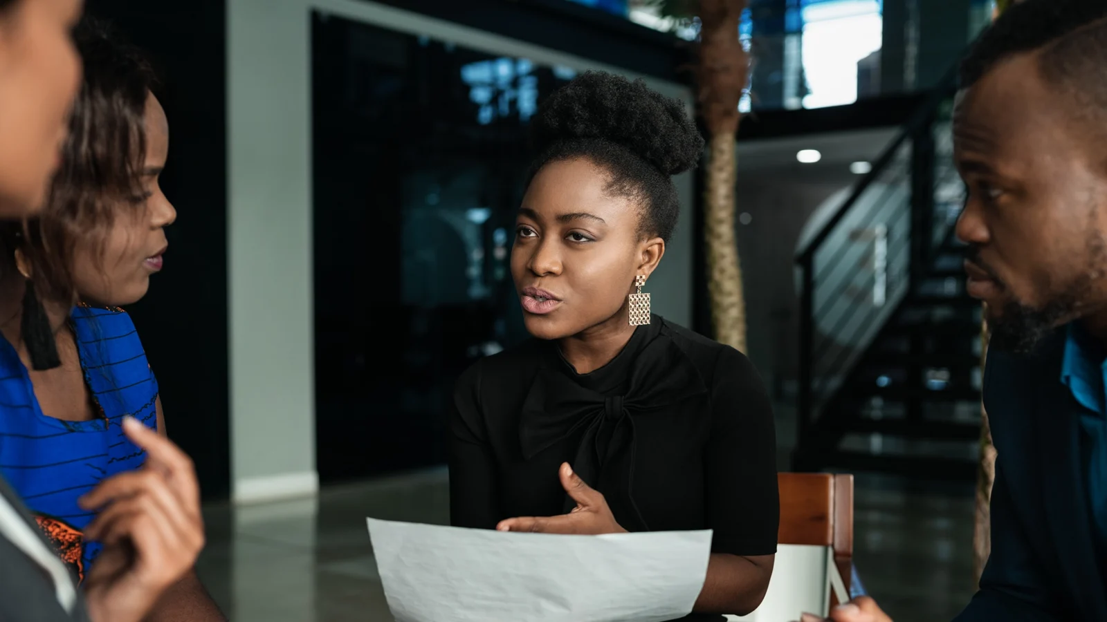 Black woman in office presenting to other workers