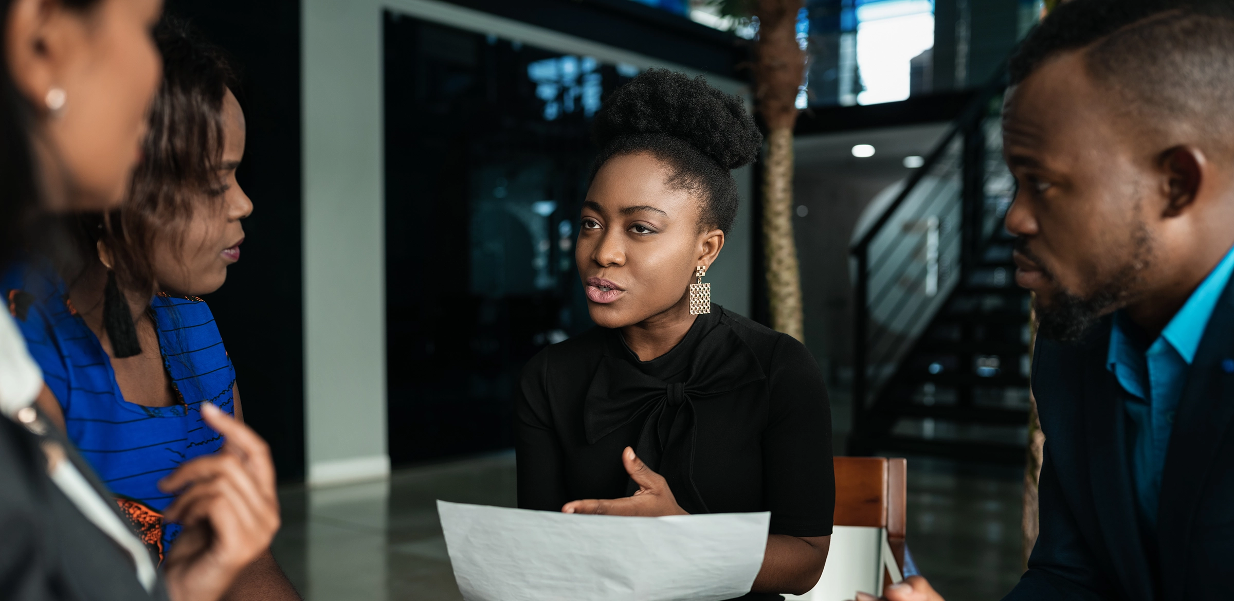 Black woman in office presenting to other workers