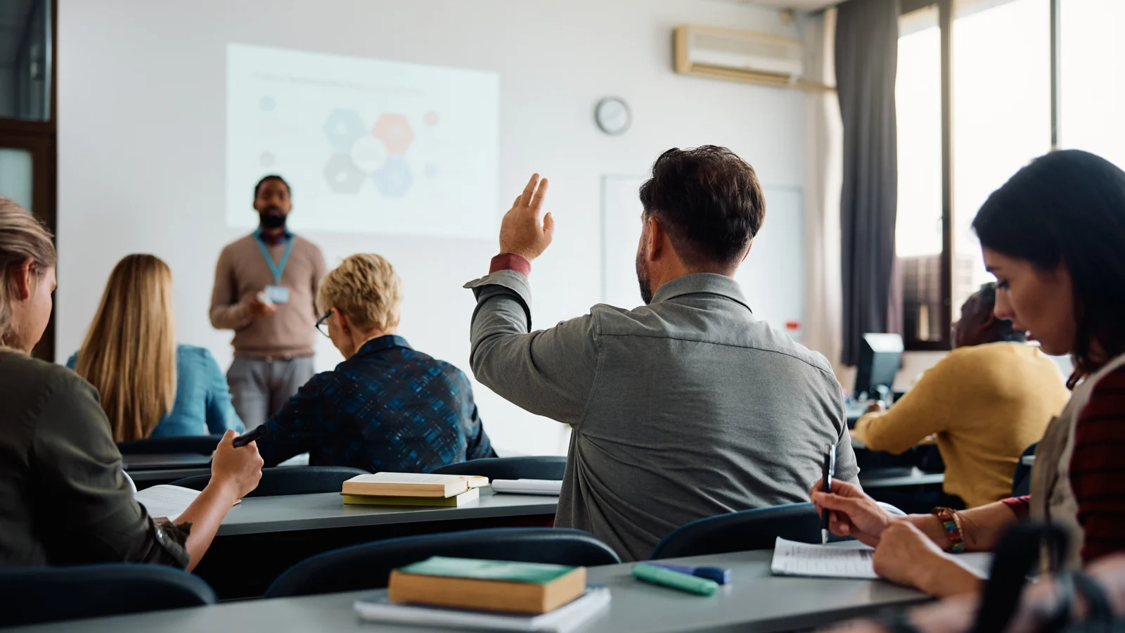 Student raising his hand in college classroom
