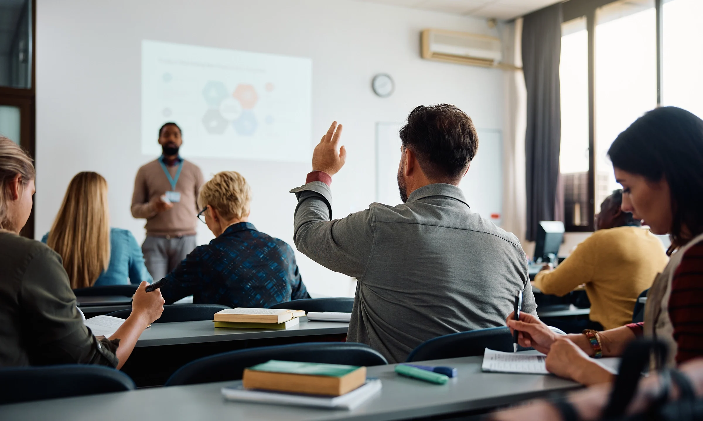 Student raising his hand in college classroom
